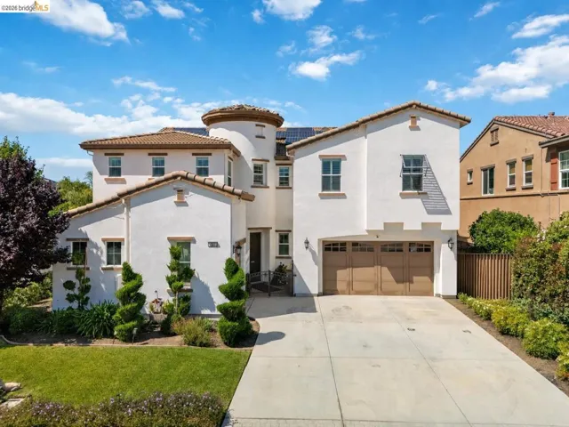 Stucco exterior residence featuring a prominent turret, multi-pane windows, and a multi-car garage with panel doors