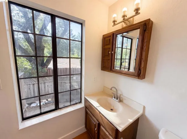 Bathroom vanity featuring a wood-finish cabinet, integrated sink, and light-toned countertop
