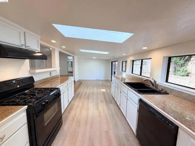 Galley kitchen featuring white cabinetry, granite-finish countertops, and wood-finish flooring