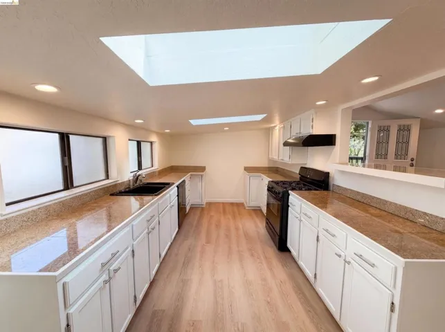 Kitchen featuring white cabinetry, granite-finish countertops, and wood-finish flooring