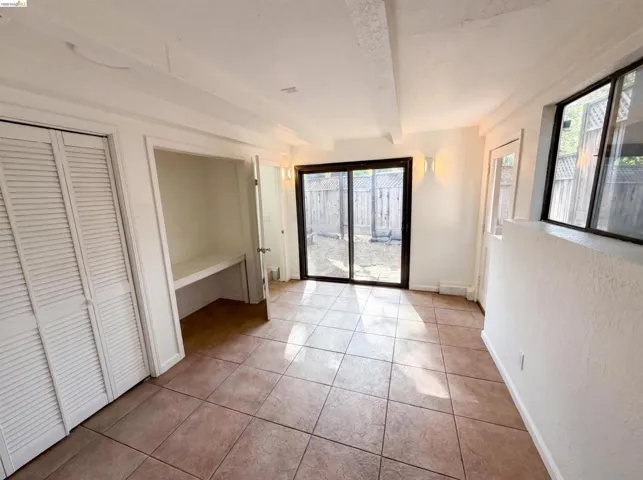 Tiled flooring, built-in desk, sliding glass door, and louvered bifold closet doors