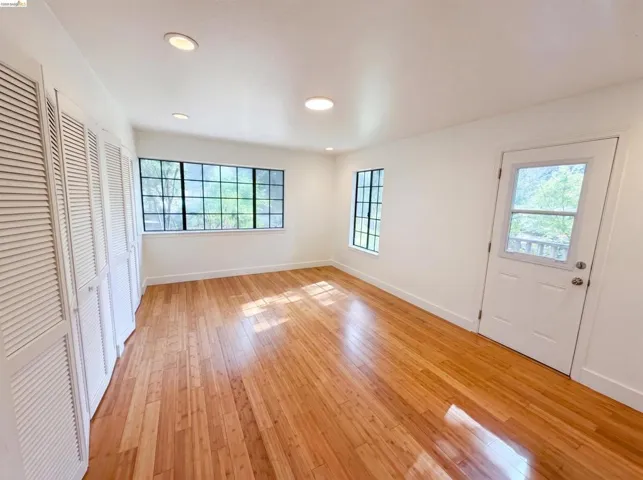 Hardwood flooring highlights this bright room featuring recessed lighting, a multi-pane window, and louvered bifold closet doors