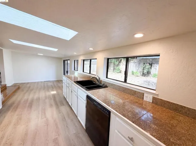 Kitchen with light wood-finish flooring, white cabinetry, and granite countertops