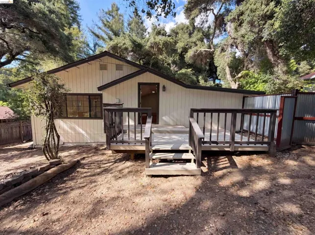 Exterior featuring light-colored vertical siding, dark trim, and a multi-level wood deck