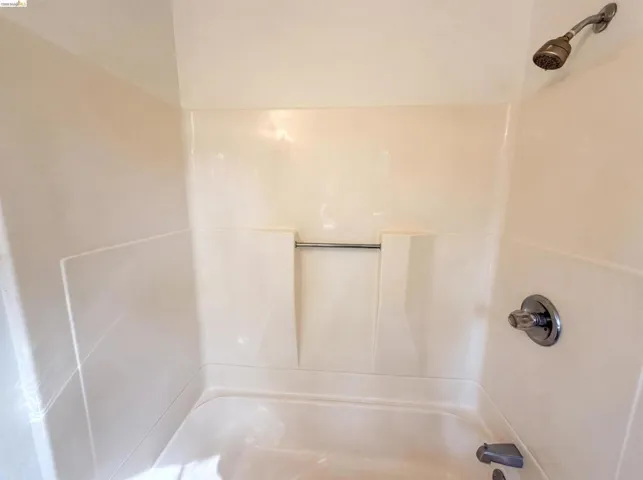 Tub and shower combination featuring a bronze shower head and chrome faucet