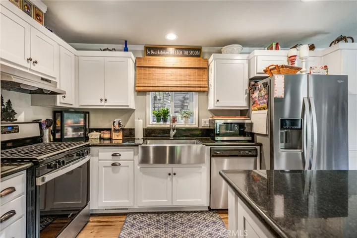 Kitchen with granite counter top, stainless steel appliances and farmhouse sink.