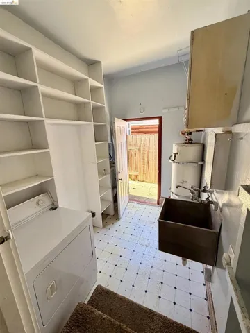 Utility space featuring built-in shelving, patterned tile flooring, a deep utility sink, and direct outdoor access