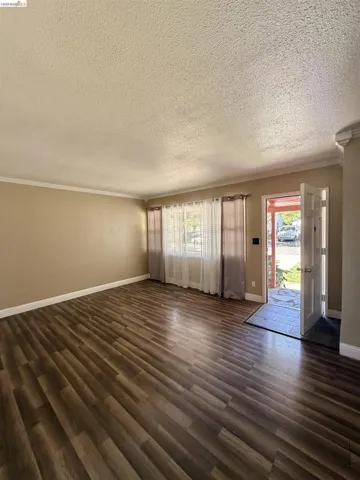 Spacious interior featuring wood-finish flooring, neutral-toned walls, and white crown molding