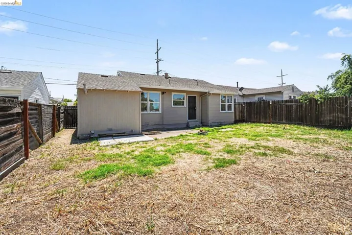 Expansive rear yard featuring a partial concrete patio and wood fencing