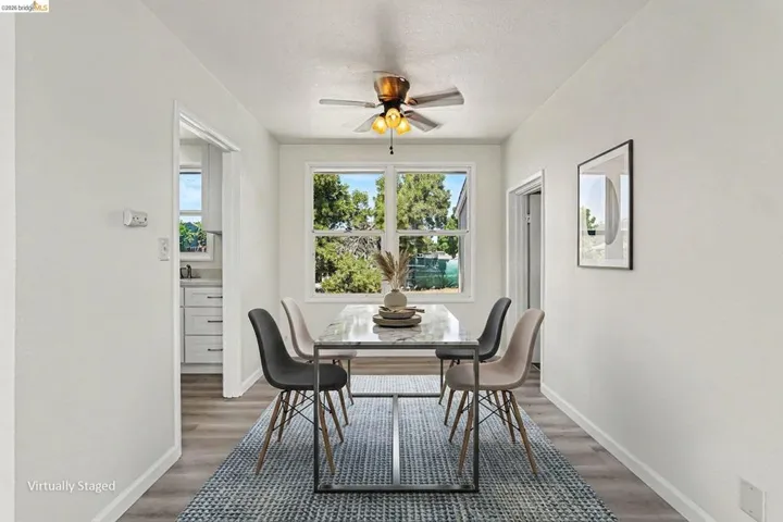 Dining area featuring a central window, warm wood-finish flooring, and a ceiling fan with integrated lighting
