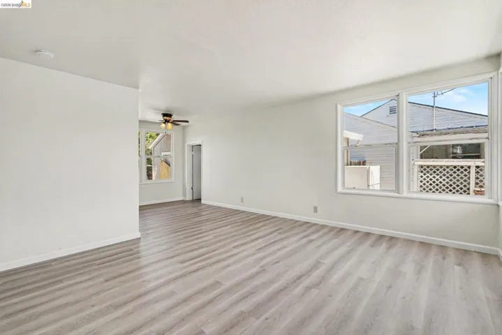 Expansive living area featuring light wood-finish flooring, white baseboards, and neutral wall paint