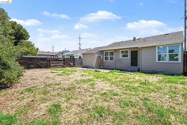 Expansive backyard with a wooden fence boundary and a light beige exterior home