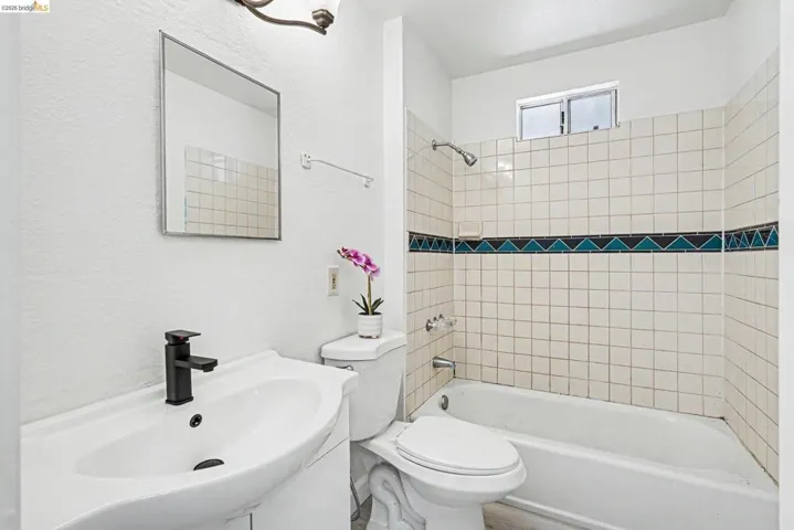Bathroom featuring a white vanity with an integrated sink, a modern matte black faucet, and a rectangular mirror