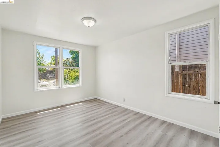 Room featuring light wood-finish flooring, white baseboards, and a neutral wall color