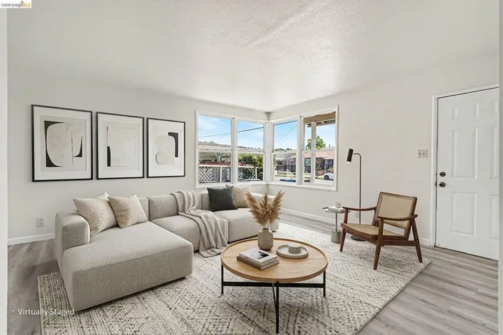 Bright living space featuring multiple windows, light-toned walls, and wood-finish flooring