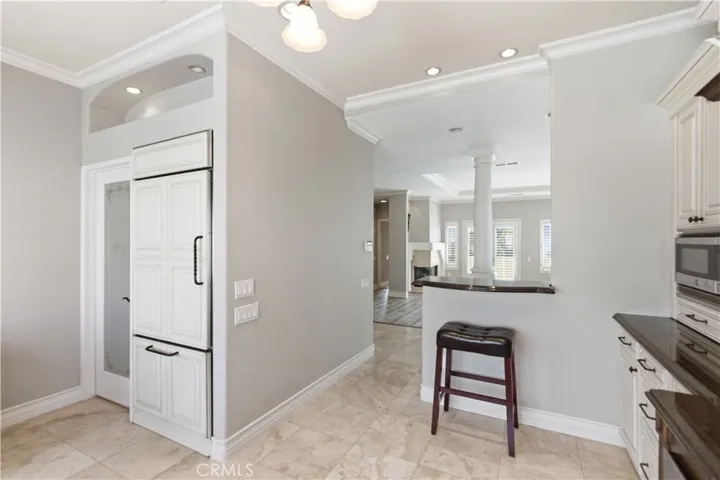 View from kitchen to walk in pantry & laundry (far left), cabinet-faced GE Profile refrigerator w/ice maker, small productivity bar or solo dining and view into living room with ocean view (can see ocean from kitchen)