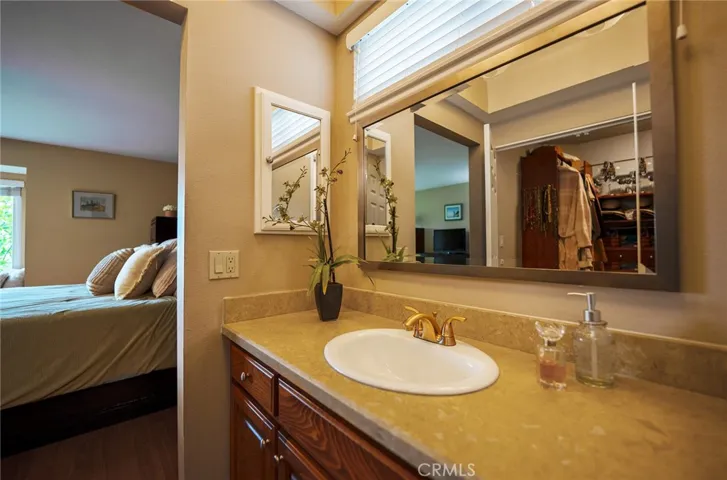 The en suite primary room bath has 2 separate sinks. The walk in closet can be seen in the mirror