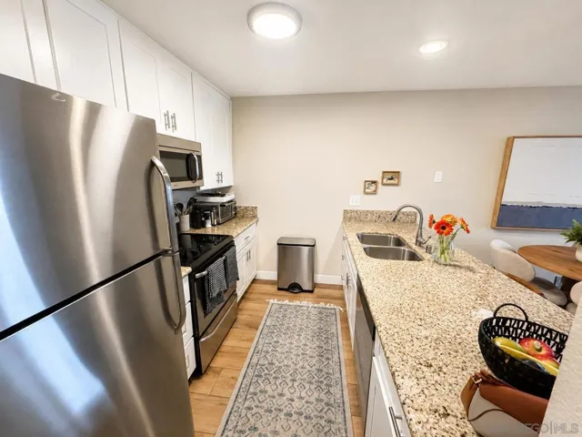 Timeless slab granite countertops, crisp white shaker cabinetry, and stainless steel appliances define this beautifully remodeled kitchen. The oversized breakfast bar provides seating for up to four and offers generous prep space for entertaining.