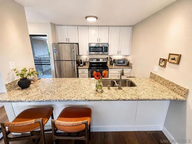 Timeless slab granite and an ultra-modern design define this beautifully remodeled kitchen. The expansive breakfast bar seats up to four and is perfect for prepping and serving large meals, with convenient access to the dining area for additional guests.