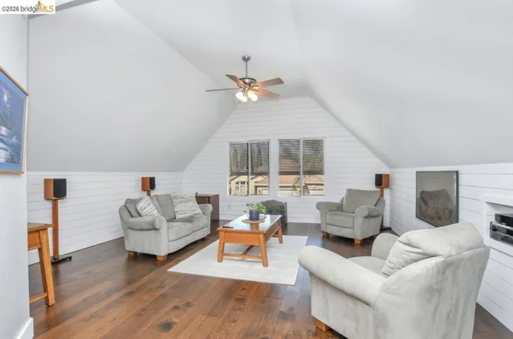 Expansive living area featuring rich wood-finish flooring, vaulted ceilings, and shiplap wall accents