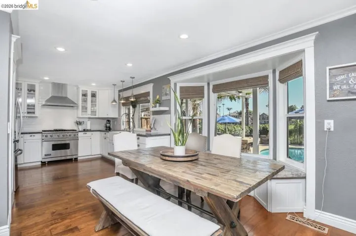Kitchen and dining area featuring hardwood flooring, white cabinetry, stainless steel appliances, and a built-in window seat