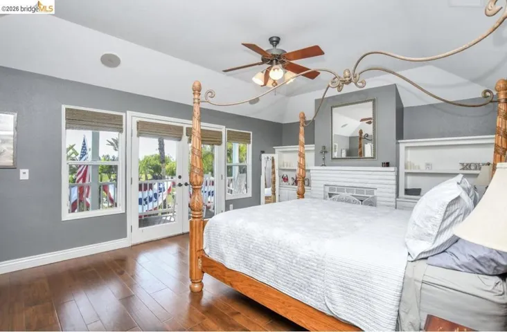 Hardwood-finish flooring featuring a vaulted ceiling and a ceiling fan with integrated lighting