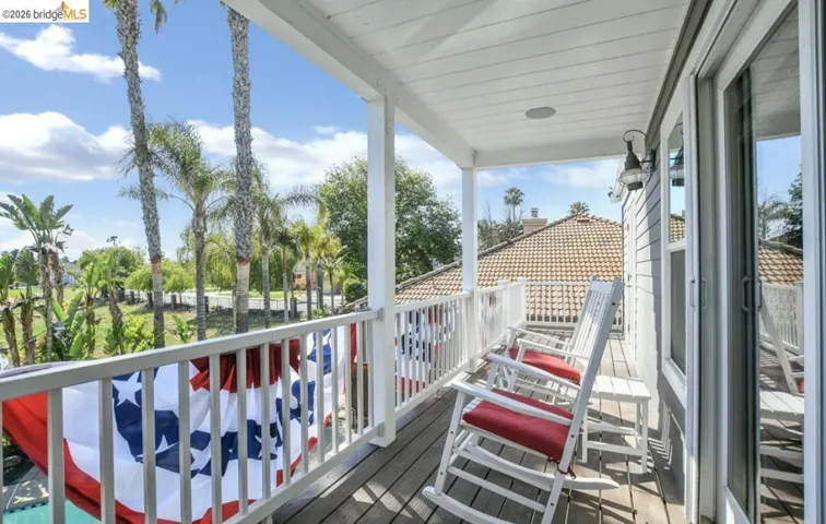Covered balcony featuring wood-finish flooring and a white railing