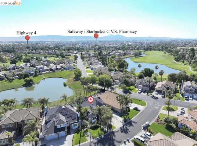 Aerial perspective showcasing a residential area with multiple properties, lush green landscaping, and prominent water features
