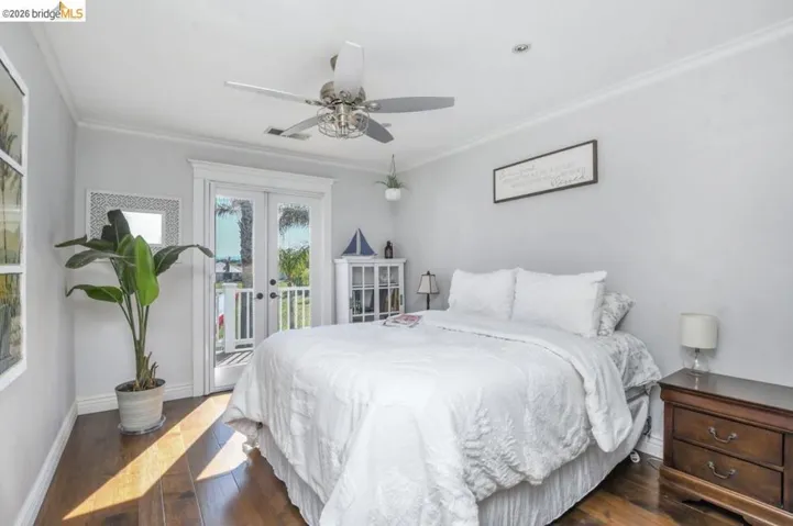 Bright bedroom featuring wood-finish flooring and crown molding