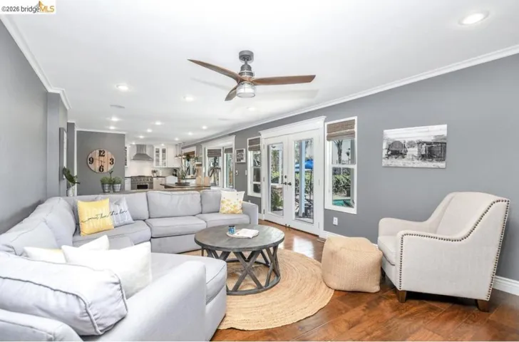 Open-concept living space with dark wood-finish flooring, recessed lighting, and crown molding