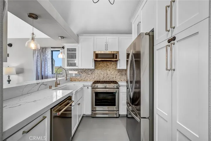 Note the dramatic quartz counters, stone backsplash & walls of cabinetry