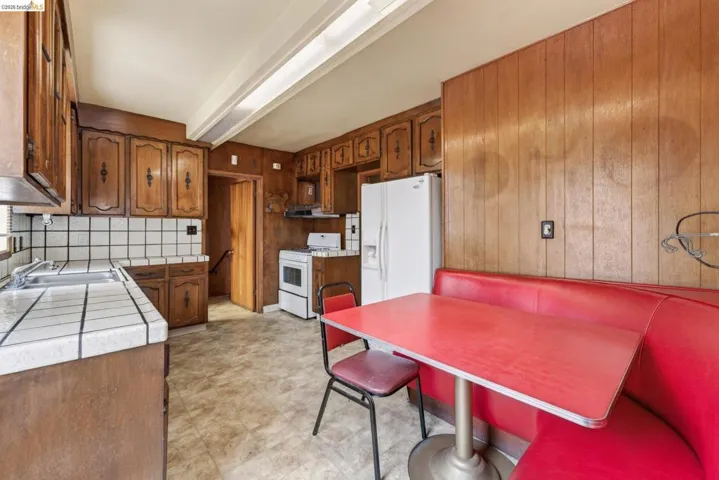 Kitchen with wood paneling, wood cabinetry, white tile countertops, and a white tile backsplash