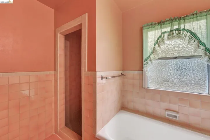 Full bathroom featuring a built-in tub, tiled walls, and a separate shower enclosure