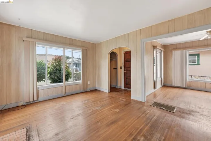 Hardwood flooring throughout, vertical wood paneling, and an arched entry