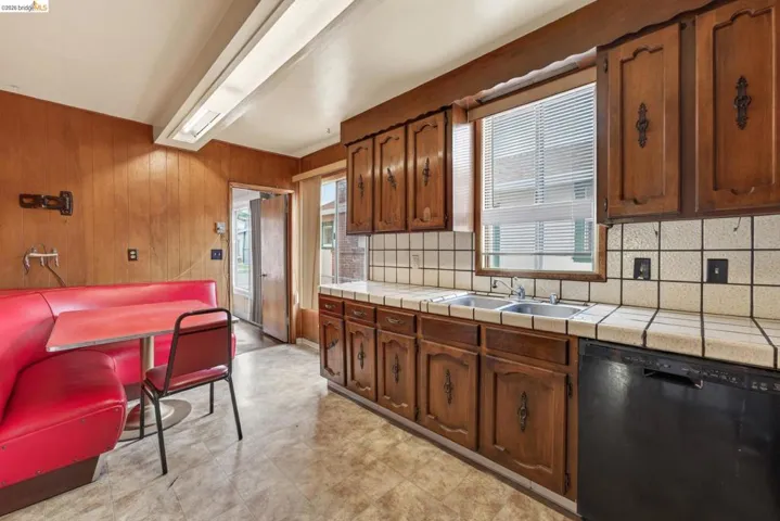 Kitchen featuring wood-paneled walls, wood cabinetry, and a tile countertop with a matching tile backsplash