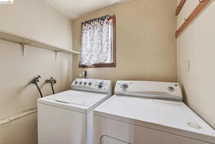 Dedicated laundry area featuring a window, built-in shelving, and wall-mounted hooks