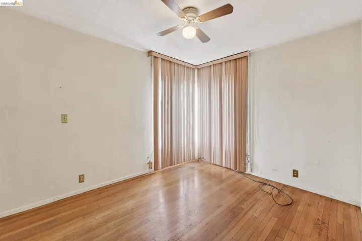 Room featuring wood-finish flooring, a ceiling fan with integrated lighting, and vertical window coverings
