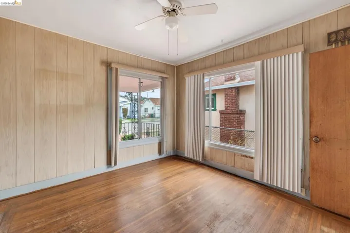 Hardwood flooring throughout featuring wood-paneled walls and a ceiling fan