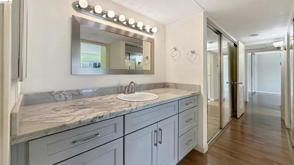 Bathroom vanity featuring light gray cabinetry, a white countertop with gray veining, and a polished chrome faucet
