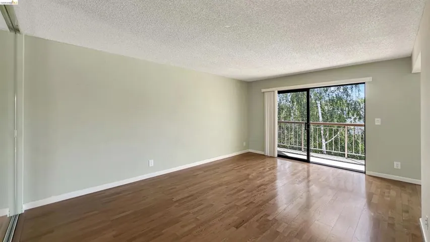 Spacious room featuring wood-finish flooring and a full-wall sliding glass door leading to a balcony