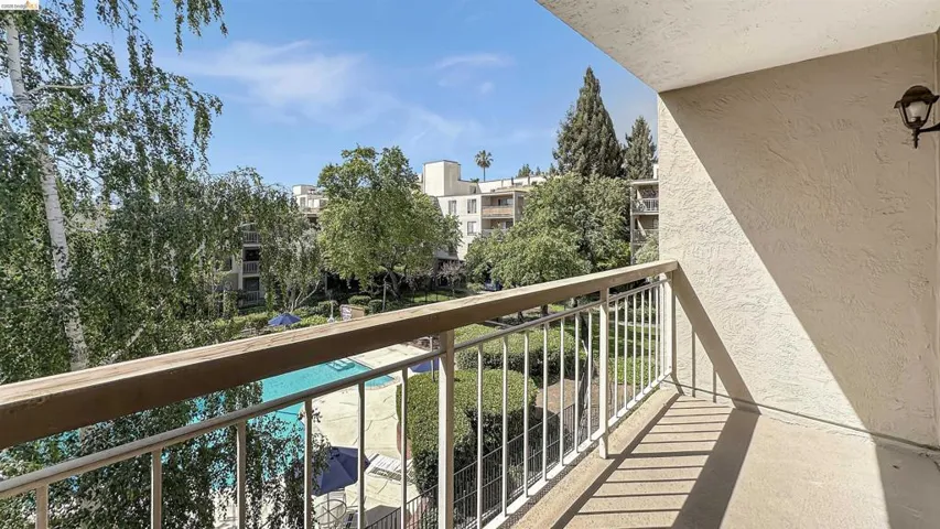 Balcony with a textured exterior wall, metal railing, and a wall-mounted light fixture