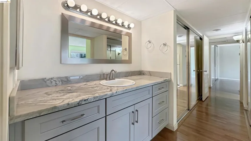 Bathroom vanity featuring light gray cabinetry, a white countertop with gray veining, and a polished chrome faucet