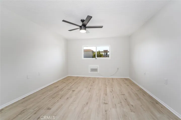 Large master bedroom with strong overhead fan and air-conditioning in wall.