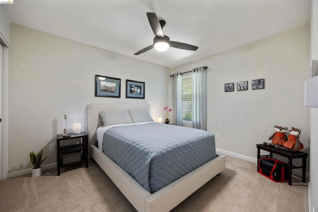 Carpeted room featuring a ceiling fan with integrated lighting, a window with blinds, and neutral wall tones