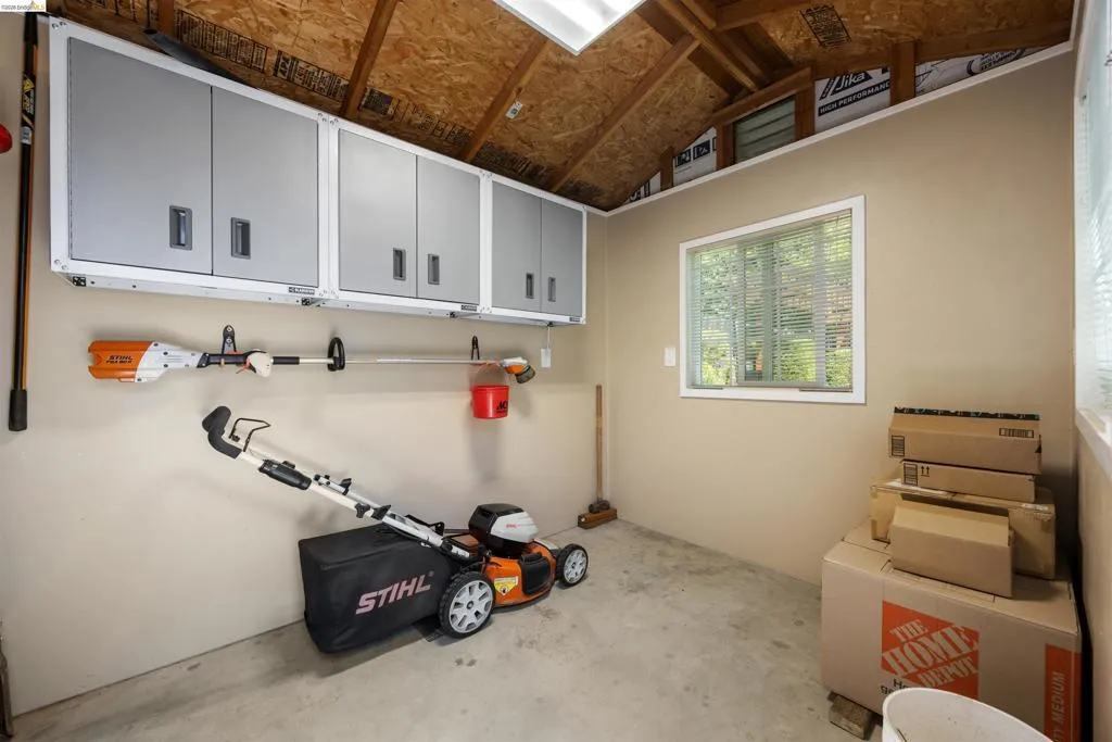 Utility shed featuring a concrete floor, painted walls, and an exposed wood beam ceiling