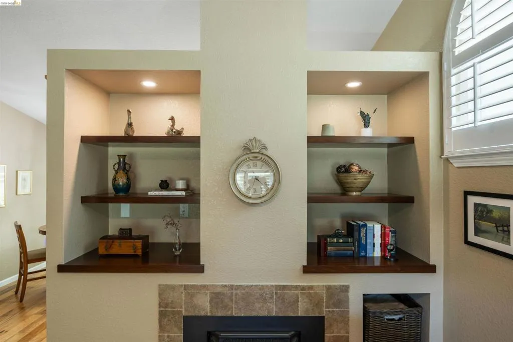 Integrated built-in shelving with recessed lighting, dark wood-finish shelves, and a tiled fireplace surround
