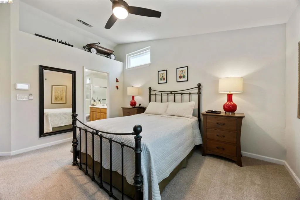 Carpeted room featuring a ceiling fan with integrated lighting, an upper ledge, and a high transom window