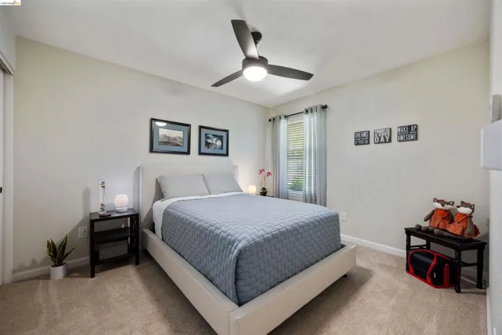Carpeted room featuring a ceiling fan with integrated lighting, a window with blinds, and neutral wall tones