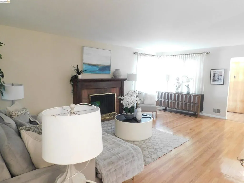 Hardwood flooring extending throughout, complemented by a prominent fireplace with a dark wood mantel and surround