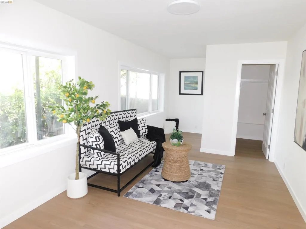 Light-filled room featuring wood-finish flooring, white baseboards, multiple windows, and a recessed ceiling light fixture